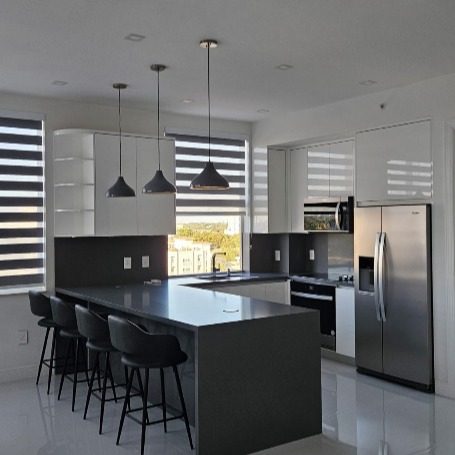 Kitchen with a large dark island, black bar stools and pendant lighting